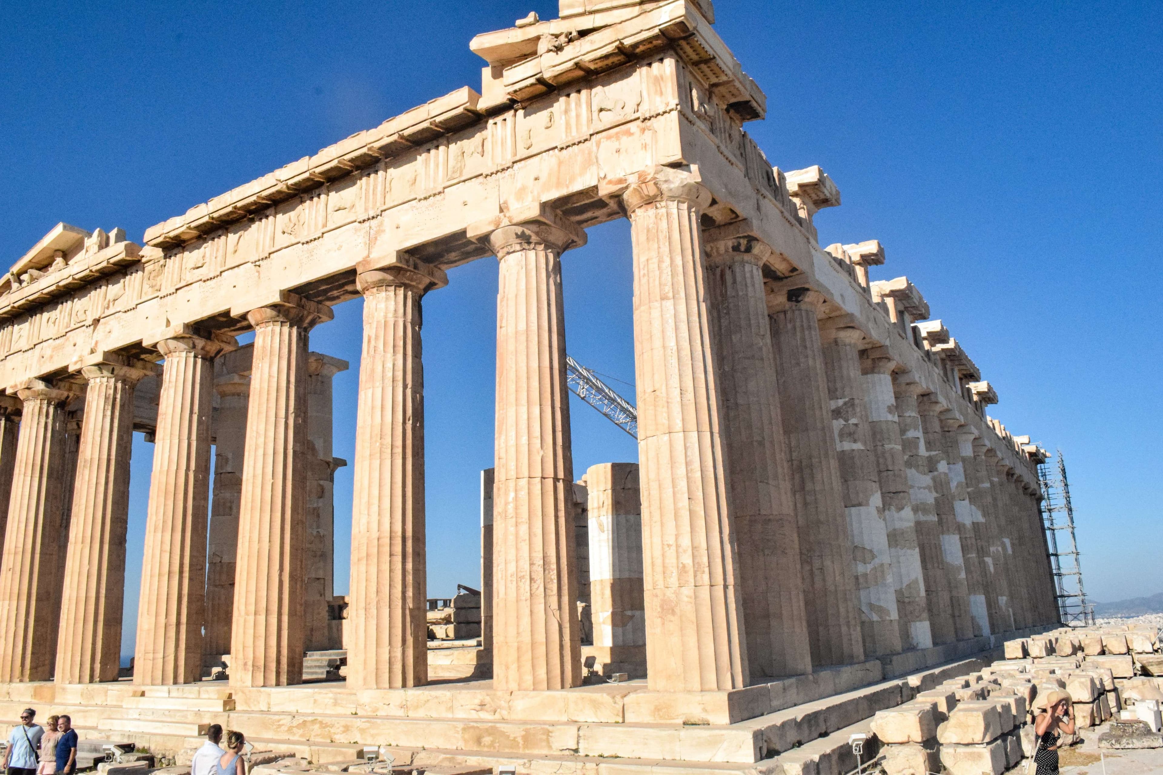 Arafed view of a large stone structure with columns and a few people.