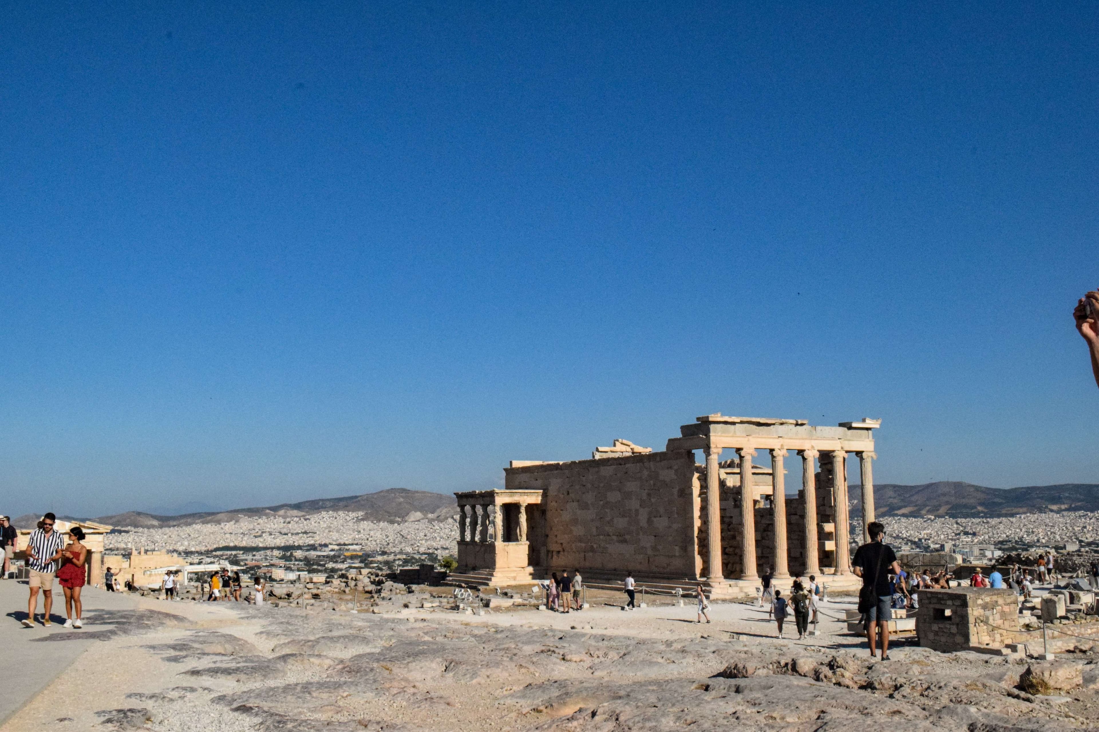 There is a man flying a kite on a clear day.