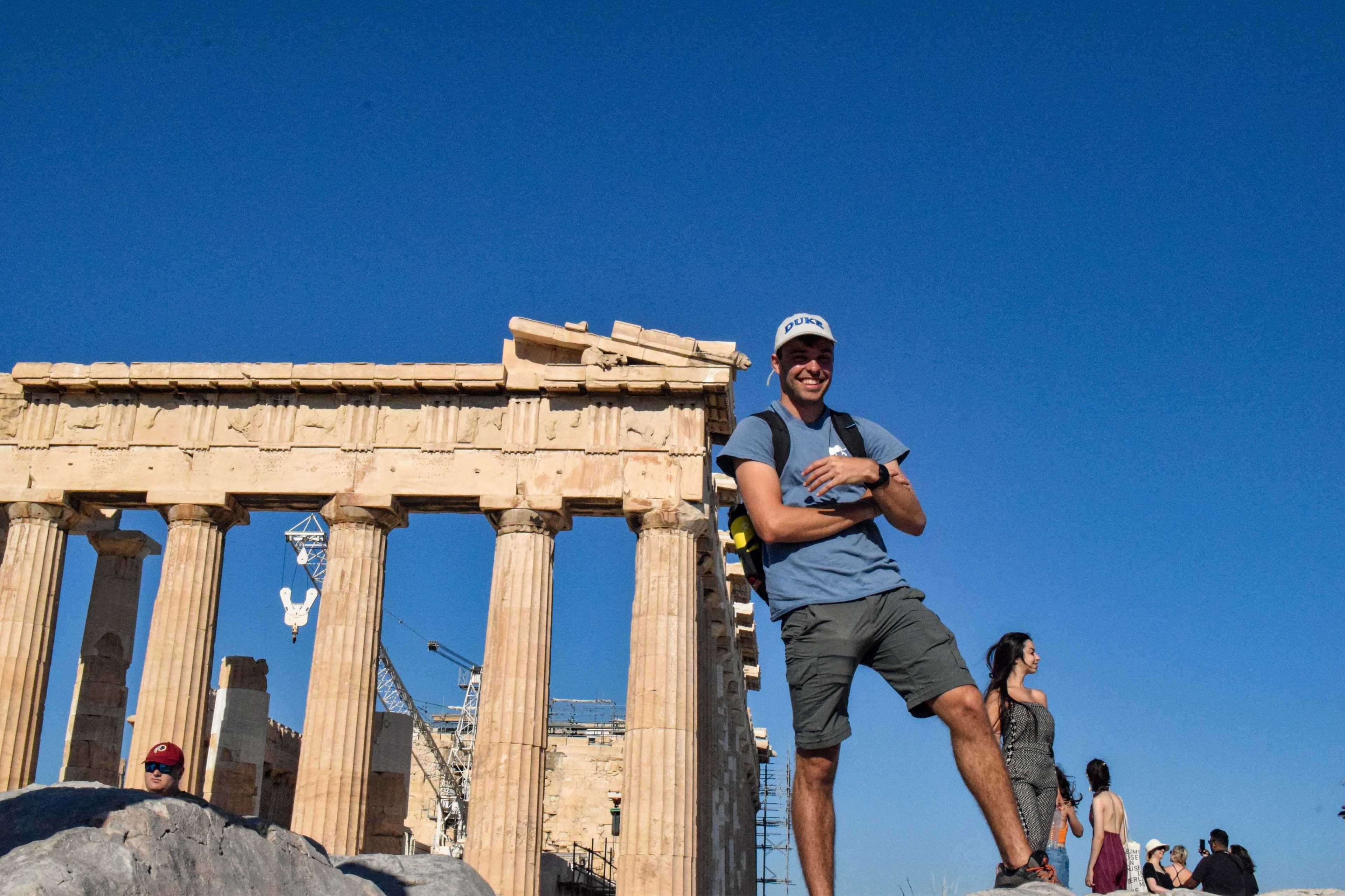 There is a man standing on a rock in front of a building.