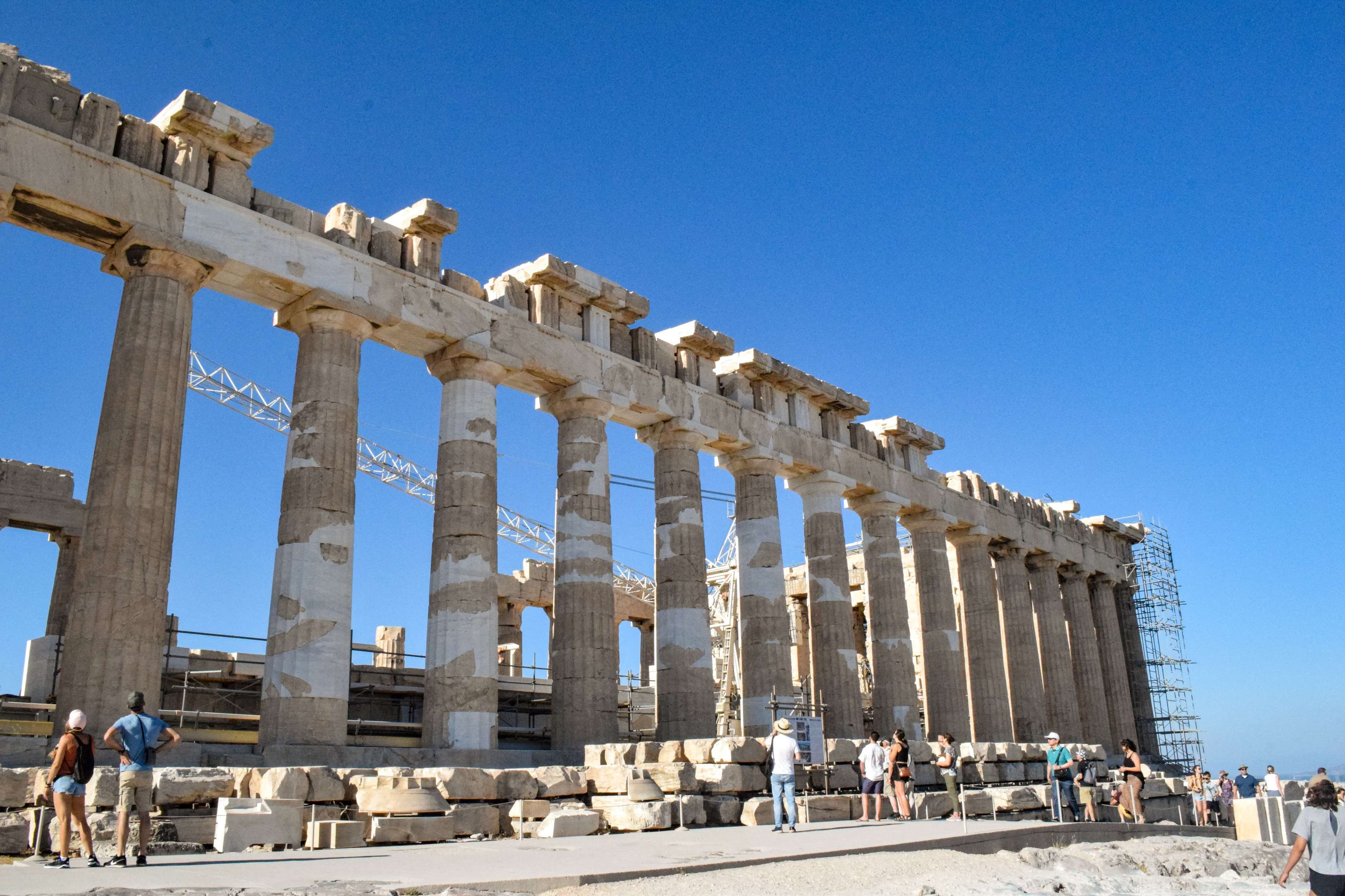 There are people standing in front of a large building with columns.