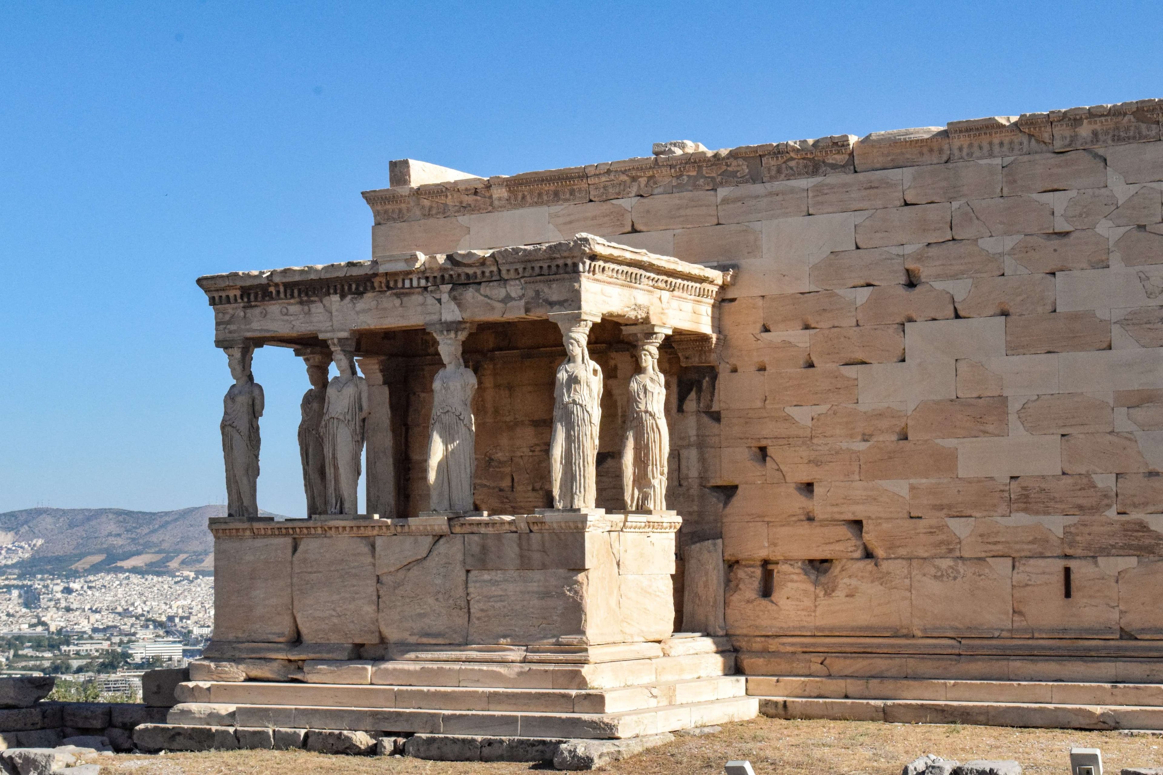There is a stone structure with statues on it in front of a mountain.